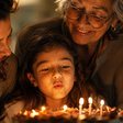 Uma menina soprando as velas do bolo, com a avó ao lado